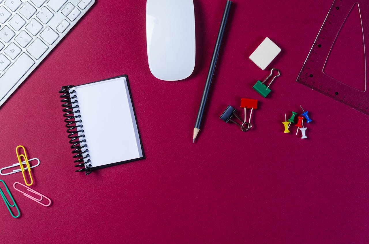 Flat lay of school supplies and office essentials on a vibrant red surface with copy space.